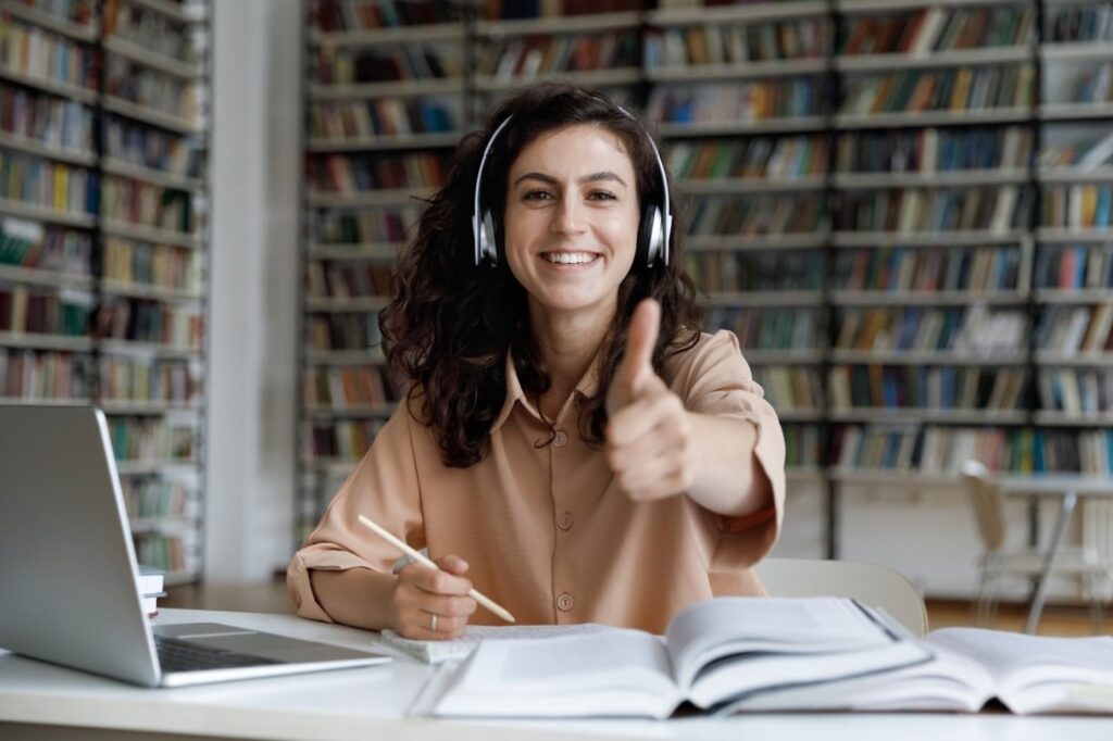 a woman wearing headphones showing a thumb